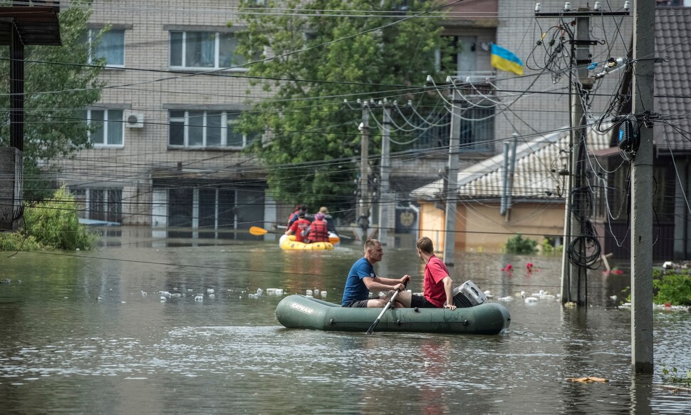 댐 붕괴로 침수된 우크라이나 남부 헤르손주에서 8일(현지시간) 주민들이 보트를 타고 대피하고 있다. 지난 6일 새벽 높이 30ｍ, 길이 3.2㎞의 카호우카 댐이 폭발과 함께 붕괴해 지금까지 최소 5명이 사망했다. 연합뉴스