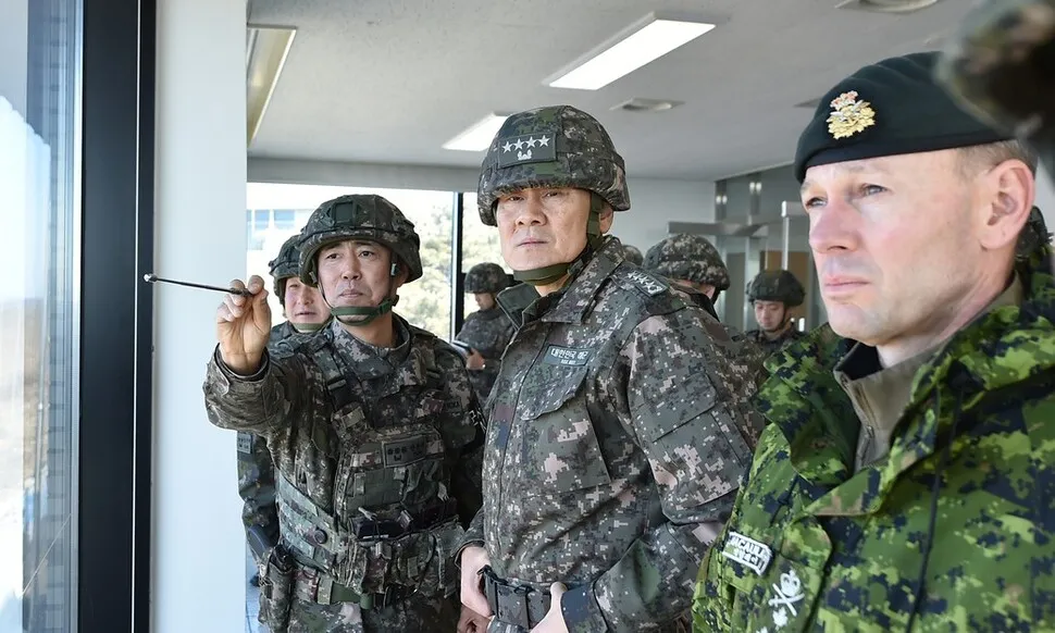 김명수 합동참모의장(가운데)과 데릭 맥컬리 유엔군사령부 부사령관(오른쪽)이 육군 1사단 예하 일반전초(GOP)대대에서 북쪽을 바라보며, 상황을 점검하고 있다. 방탄헬멧을 쓴 김명수 의장과 달리 맥컬리 부사령관은 천으로 만든 베레모 차림이다. 두 사람의 모자가 다른 것은 1사단 방문 목적이 김 의장은 군사대비 태세 점검이고 맥컬리 부사령관은 ‘남북 간 정전협정 준수’이기 때문이다. 합동참모본부 제공