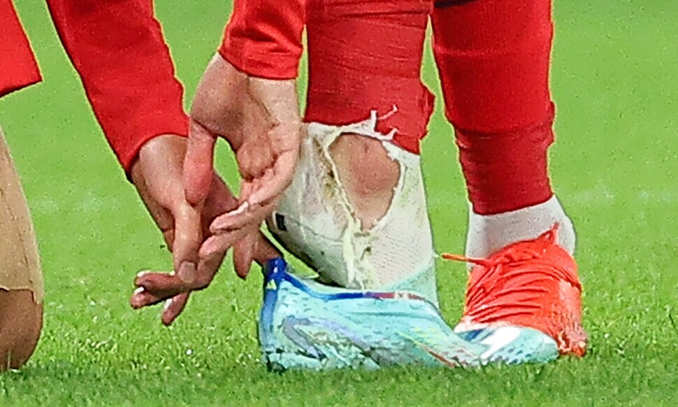 Son Heung-min of the Korean national team slips his foot back into his cleat after being tackled by Martin Caceres of Uruguay during the Group H opening match at the 2022 FIFA World Cup in Qatar.