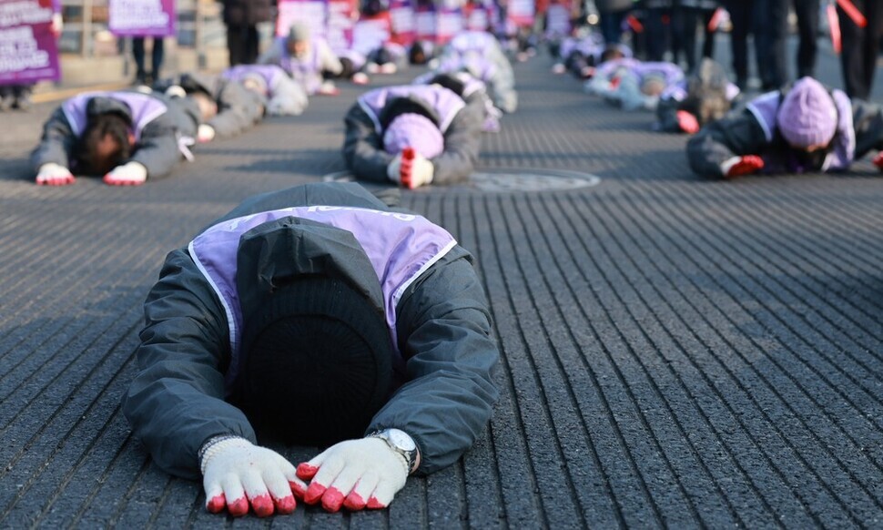 People who lost loved ones in the 2022 Halloween crowd crush in Itaewon lie prostrate on the road as they make their way from the site of the disaster that claimed the lives of their family members to the presidential office in Yongsan, 1.5 kilometers away, on Jan. 29 to call for the enactment of a special act that would carry out a fact-finding investigation into the disaster. (Kim Hye-yun/The Hankyoreh)