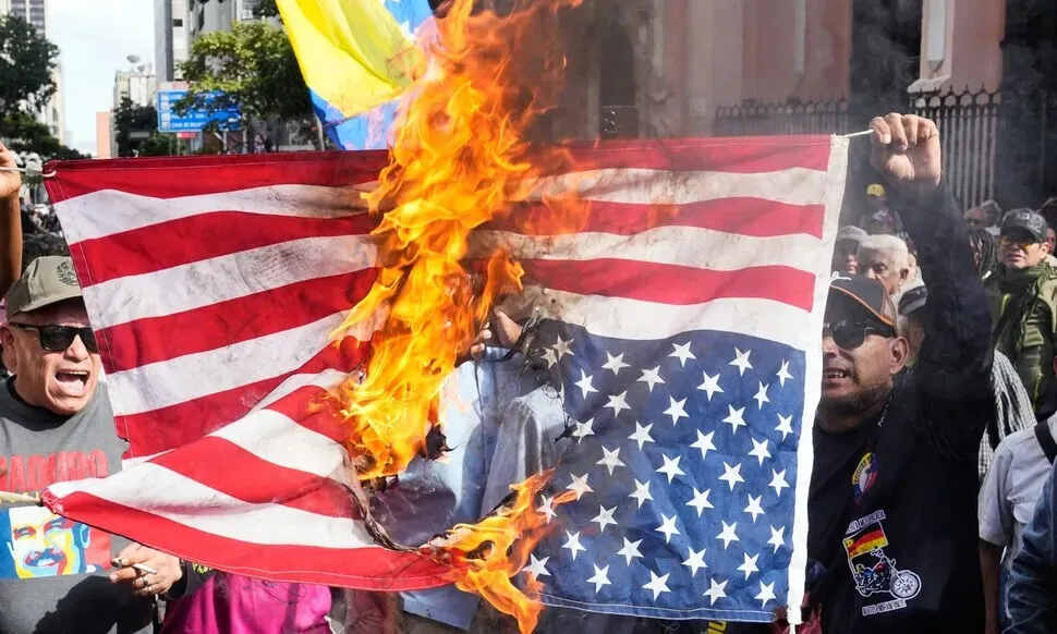 Venezuelans protesting the abduction of their president, Nicolás Maduro, by the US burn an American flag at a rally held in Caracas on Jan. 3, 2026. (AP/Yonhap) 