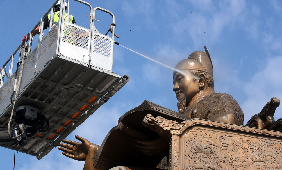 A city worker hoses down the statue of King Sejong the Great that sits in Gwanghwamun Square in downtown Seoul on July 18. (pool photo)