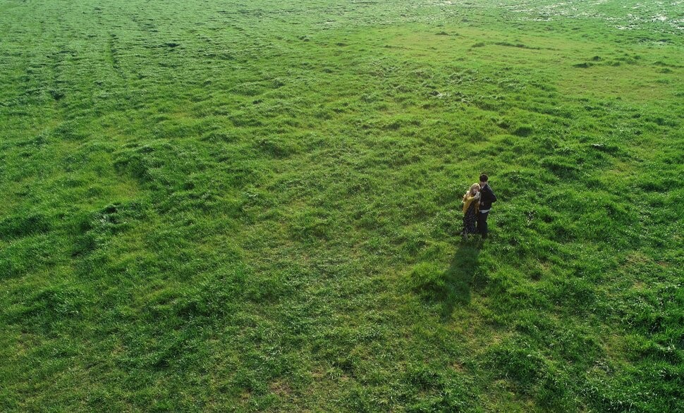 풀이 성큼 자란 서귀포 표선면 말 목장을 배경으로 한 쌍의 남녀가 사진을 찍고 있다.
