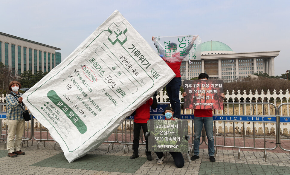 Members of Greenpeace hold a protest Wednesday in front of the National Assembly, criticizing its recent climate change bills for their omission of a definite greenhouse gas reduction goal. (Kang Chang-kwang/The Hankyoreh)