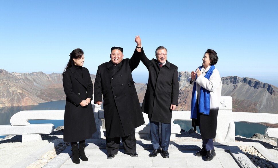 South Korean President Moon Jae-in and North Korean leader Kim Jong-un clasp hands and raise them high over their heads at the top of Mount Baekdu