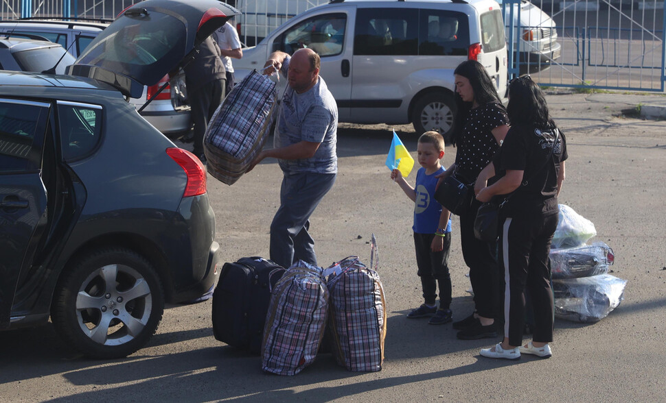 Um homem carrega os pertences de sua família de Varsóvia, na Polônia, na manhã do dia 13 (horário local) para um ponto de ônibus em Zhytomyr, na Ucrânia.  Escrito por Zhitomir / Kim Hye Yoon, repórter da equipe