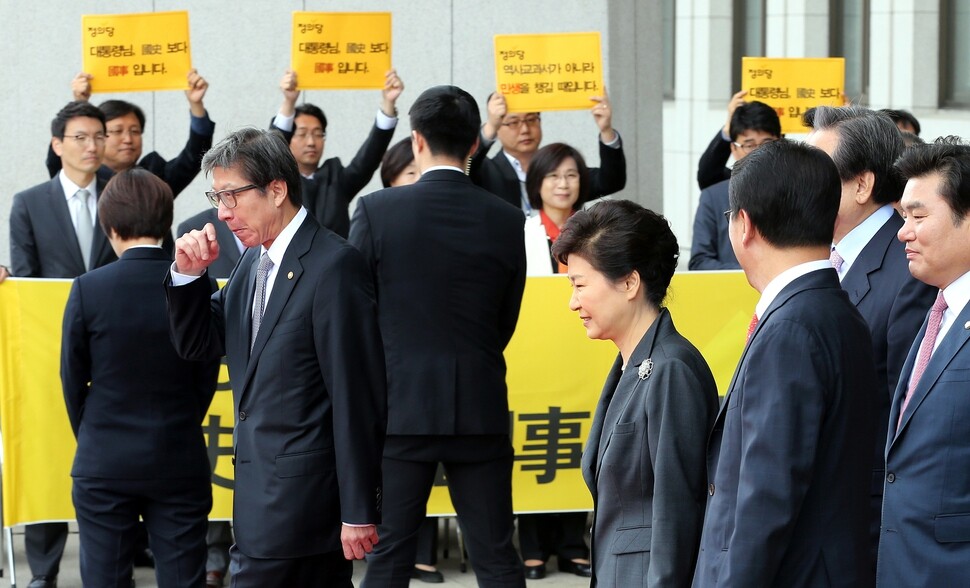 박근혜 전 대통령이 2015년 10월27일 국회에서 시정연설을 끝내고 김무성 당시 새누리당 대표 등 지도부의 안내를 받으며 퇴장하는 가운데, 정의당 의원단이 국정화 반대 피켓 시위를 하고 있다. 한겨레 김경호 선임기자