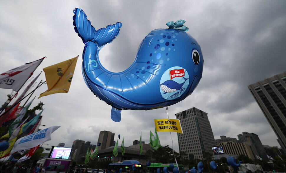 A whale-shaped balloon with a sticker bearing a message opposing the dumping of radioactive wastewater from the Fukushima nuclear power plant into the ocean floats above protesters as they march toward the Japanese Embassy in Seoul. (Kim Jung-hyo/The Hankyoreh)