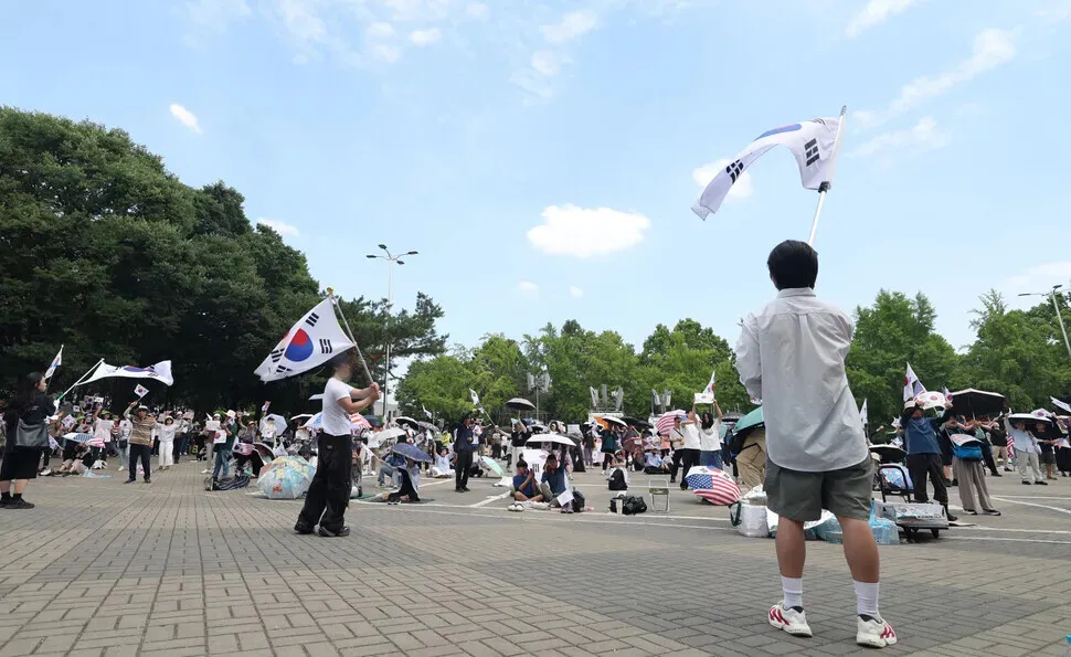 Protesters outside the handball stadium in Seoul's Olympic Park on June 17, 2026, wave Korean flags and chant slogans about holding a revote and election fraud. (Choi Hyeon-su/Hankyoreh)
