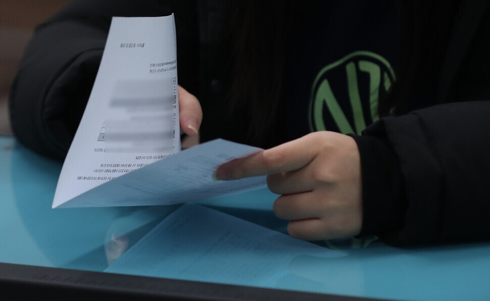  A high school senior in Changwon, South Gyeongsang Province, cautiously opens their results of the 2023 CSAT on Dec. 9, when scores were sent out to test takers. (Yonhap)