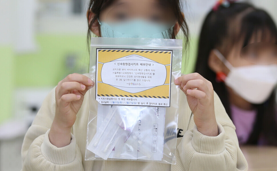 A student at one preschool in Seoul’s Guro District holds up a rapid antigen COVID-19 test kit that was passed out by their teacher on Tuesday. (pool photo)