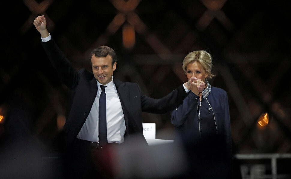 5월7일(현지시각) 프랑스 역사상 최연소 대통령에 당선된 에마뉘엘 마크롱이 부인 브리지트 트로뇌와 함께 파리 루브르 광장에서 열린 당선 축하 행사 무대에 올라 환호하는 지지자들을 향해 손을 들어 보이고 있다. REUTERS 연합