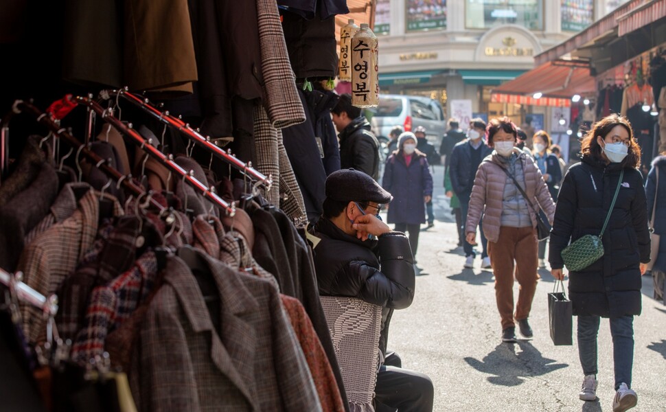코로나19 여파로 전통 시장을 찾는 손님이 크게 줄었다. 2월11일 서울 남대문시장에서 마스크를 쓴 시민들이 가게 앞을 지나는 동안 역시 마스크를 쓴 상인이 턱을 괸 채 자리를 지키고 있다.