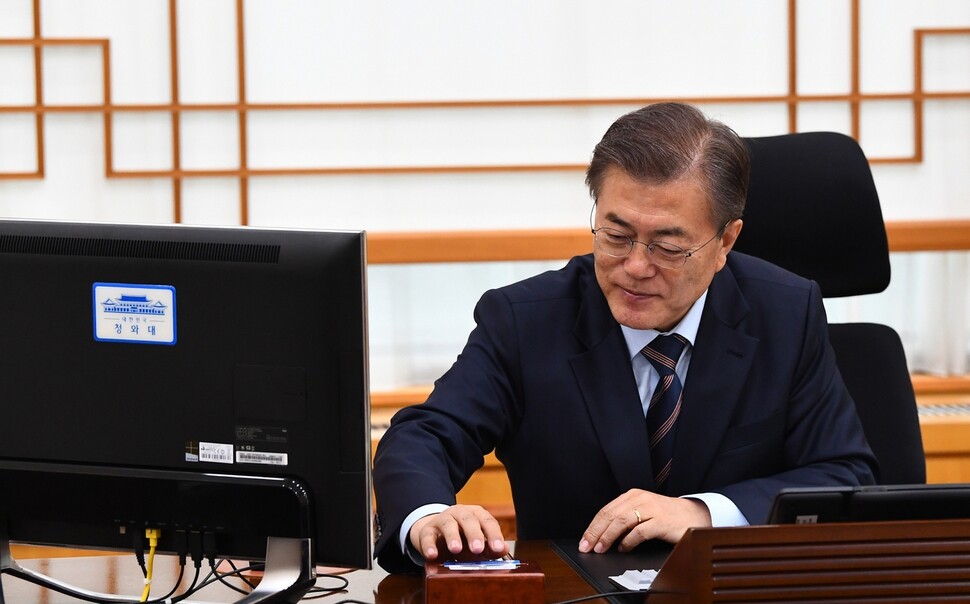 President Moon Jae-in signs a directive to mandate singalongs of “March of the Beloved” and to cancel plans for state-authored history textbooks in his office at the Blue House in Seoul