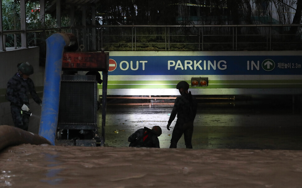 Search crew members check the water level in an underground parking lot in the Indeok neighborhood of Pohang that flooded during Typhoon Hinnamnor, trapping multiple people inside. (Kim Jung-hyo/The Hankyoreh)