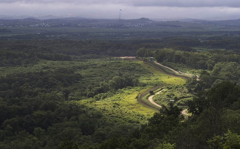 비무장지대(DMZ) 남방한계선 철책 너머로 북한 기정동 마을과 높이 솟은 인공기가 보인다. 정전 65돌을 앞둔 여름 풍경이다.