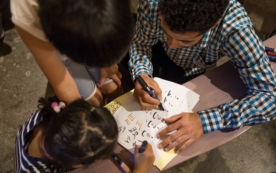 제주도민과 예멘 난민 사이의 이해를 돕기 위해 마련된 ‘제주 컬러풀 워크숍’ 행사에서 한국 어린이와 예멘 난민들이 서로의 문자를 가르쳐주고 있다. 2018년 8월8일.
