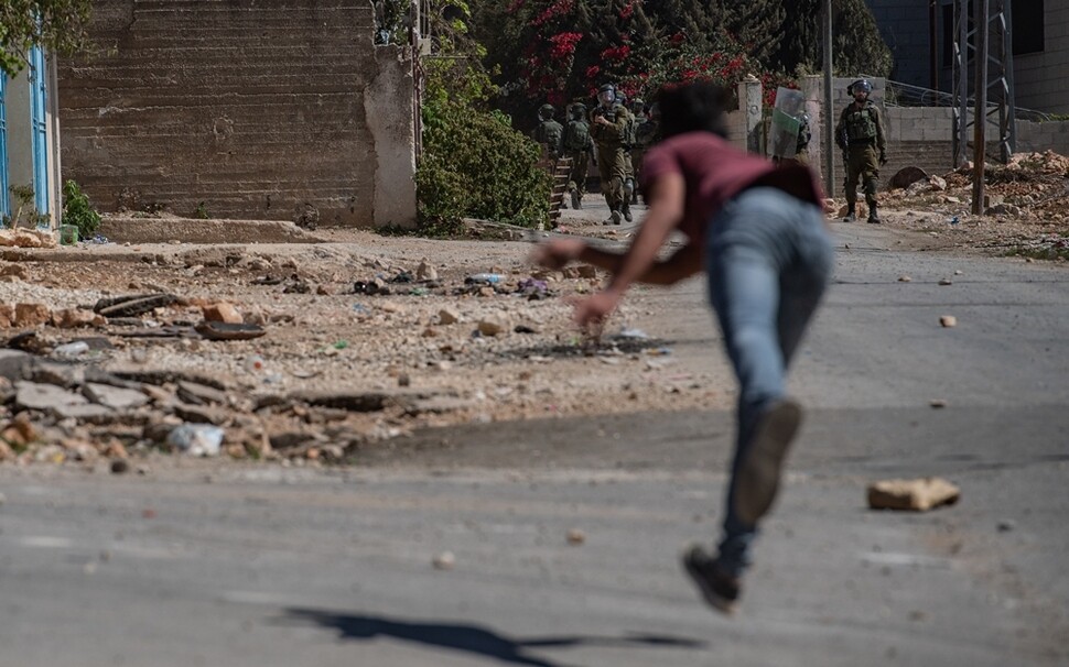 쿠프르카둠 마을 주민들이 금요일 점심 기도 뒤 집회를 하던 중 마을로 진입한 이스라엘 군인들에게 돌을 던지며 맞서고 있다.