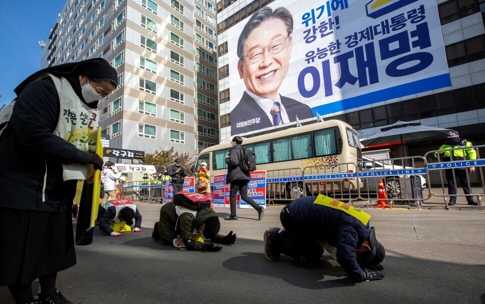 기후위기비상행동과 삼척석탄화력반대투쟁위원회, 종교환경회의, 초록교육연대, 가톨릭기후행동 회원들이 2월18일 이재명·윤석열 대선 후보의 홍보 펼침막이 각각 걸린 서울 여의도동 더불어민주당과 국민의힘 당사 앞에서 삼보일배를 하고 있다.