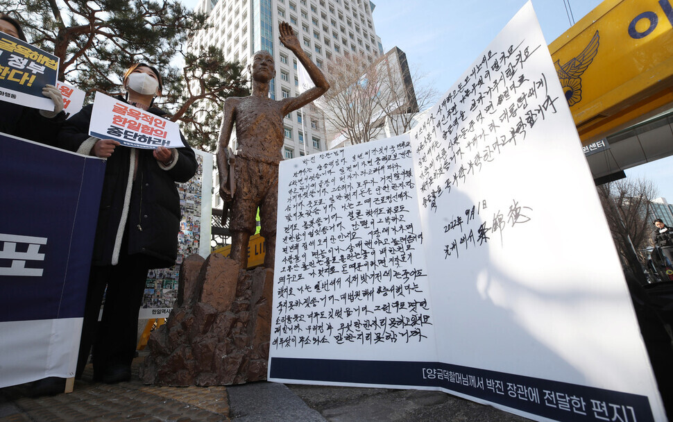 An enlarged letter written by Yang Geum-deok, a victim of forced mobilization, stands next to a statue depicting Korean victims of forced mobilization. (Shin So-young/The Hankyoreh)