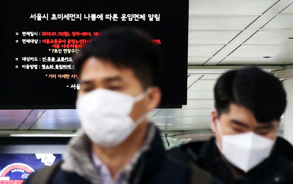 Citizens wearing masks to protect themselves from fine dust walk under a sign advising of an air quality emergency at Gwanghwamun Station in Seoul on Jan. 15. (by Baek So-ah