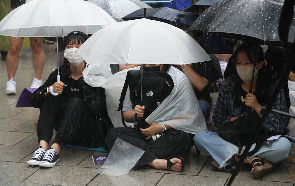 Participants in the 1,550th Wednesday Demonstration calling for the resolution of the issue of wartime sexual slavery by the Japanese military sit in the rain outside the former Japanese Embassy in downtown Seoul on June 29, calling for an apology and compensation from Japan. (Kim Jung-hyo/The Hankyoreh)