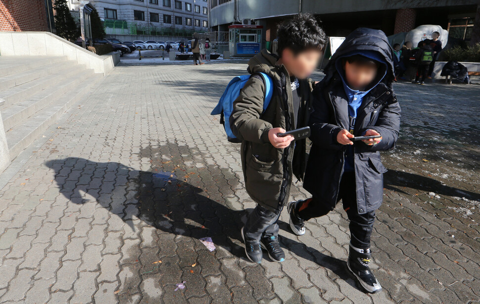 2023년 11월 서울 한 초등학교 어린이들이 수업이 끝난 뒤 스마트폰을 들여다보고 있다. 타인의 얼굴을 볼 시간이 줄어든 세대의 감수성은 이전과 다를 수밖에 없다. 한겨레 김정효 기자
