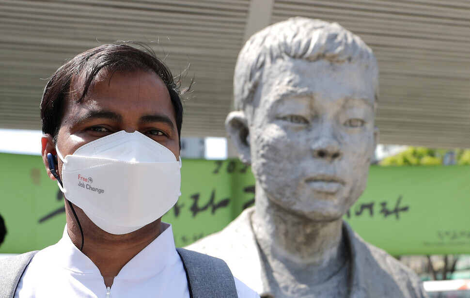 A migrant worker participating in a march for migrant labor rights poses for a picture in front of a statue of Jeon Tae-il on Sunday. (Lee Jong-keun/The Hankyoreh)