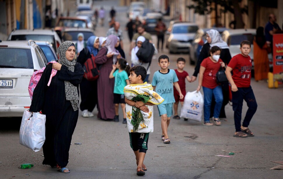 Palestinian women and children carry bags and blankets as they evacuate from Gaza City in the Gaza Strip on Oct. 13 to safer areas. (AFP/Yonhap)