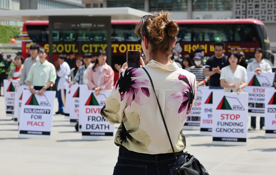 A passing tourist pauses and takes a photo of the protest outside the US Embassy. 