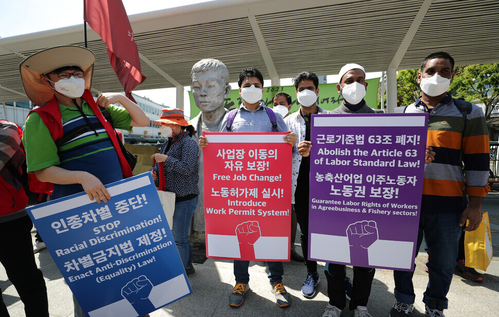 Migrant workers participating in a march for migrant labor rights pose for a picture in front of a statue of Jeon Tae-il on Sunday. (Lee Jong-keun/The Hankyoreh)