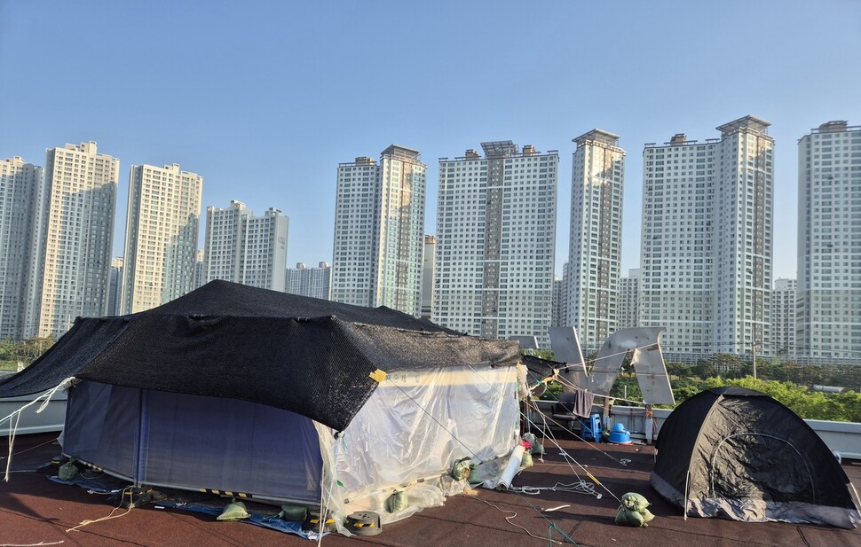 고공농성 500일을 열흘 앞둔 2025년 5월11일, 경북 구미 한국옵티칼하이테크 옥상의 고공농성장. 맞은편에 대단지 아파트가 들어서 있다. 신다은 기자