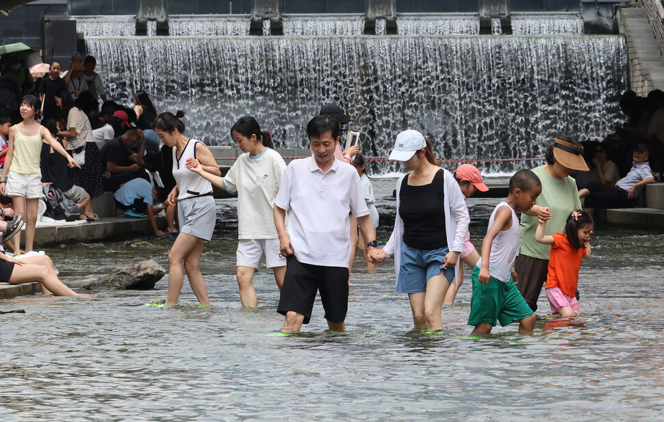 7월31일 오후 청계폭포와 광통교 사이 청계천에 발을 담근 시민들이 물속을 걷고 있다.