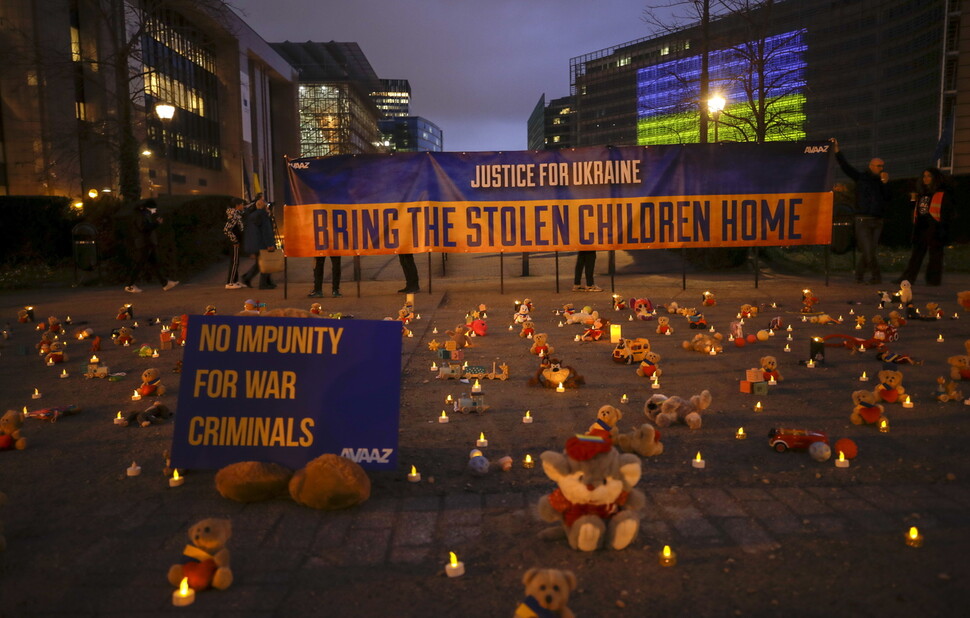 2023년 2월23일, 벨기에 브뤼셀의 유럽연합(EU) 건물 앞 광장에 시민단체 회원과 우크라이나 난민들이 장난감들을 놓고 러시아의 우크라이나 어린이 납치에 항의하고 있다. 펼침막에 “훔쳐간 아이들을 집으로 돌려보내라”고 쓰였다. EPA 연합뉴스