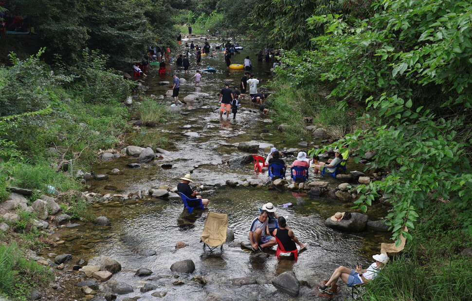 중미산에서 흘러내린 물이 지나는 신복천에서 시민들이 물속에 놓아둔 의자에 앉아 쉬고 있다.