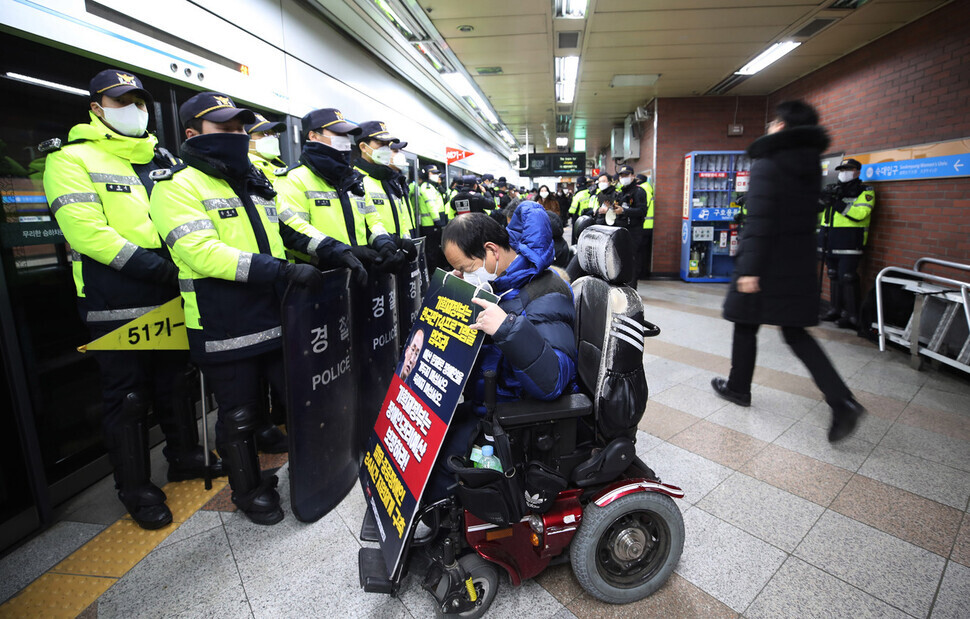 Police with riot shields block a wheelchair-using participant in SADD’s protest at Samgakji Station in Seoul from boarding the train on Jan. 2. (Shin So-young/The Hankyoreh)