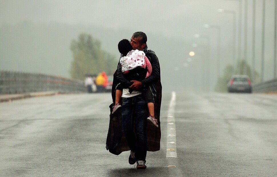 시리아 난민이 2015년 9월10일 비바람 속에 그리스의 이도메니 마을에서 마케도니아 국경을 향해 걷던 중 딸의 뺨에 입 맞추고 있다. 암 투병 끝에 3월2일 타계한 <로이터통신> 사진기자 야니스 베라키스는 이 사진을 비롯한 난민 취재 사진으로 자신의 팀과 함께 2016년 퓰리처상을 받았다.