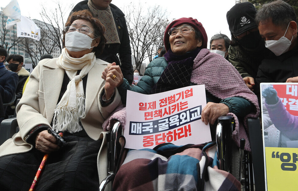 Lee Yong-soo and Yang Geum-deok, respective survivors of Japan’s systems of sexual slavery and forced labor, hold hands at a rally held on March 1 calling for a formal apology and compensation from Japan. (Shin So-young/The Hankyoreh)