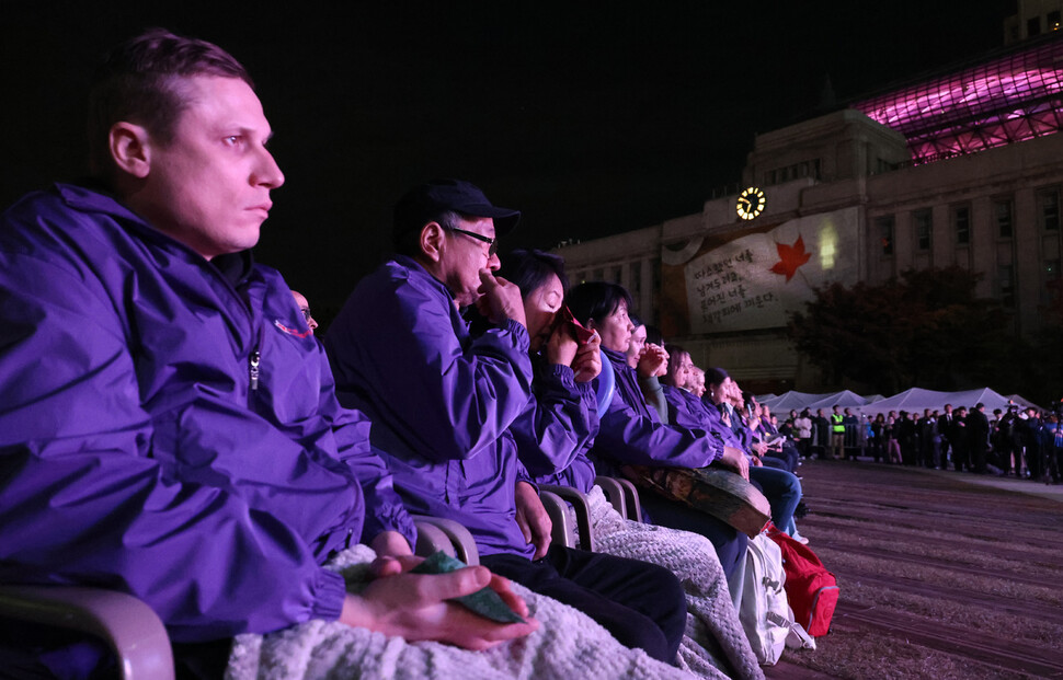 보랏빛 점퍼를 입은 이태원 참사 국내외 유가족들이 2025년 10월25일 저녁 열린 3주기 시민추모대회에서 희생자 한명 한명의 이름이 불리는 동안 흐르는 눈물을 닦고 있다.