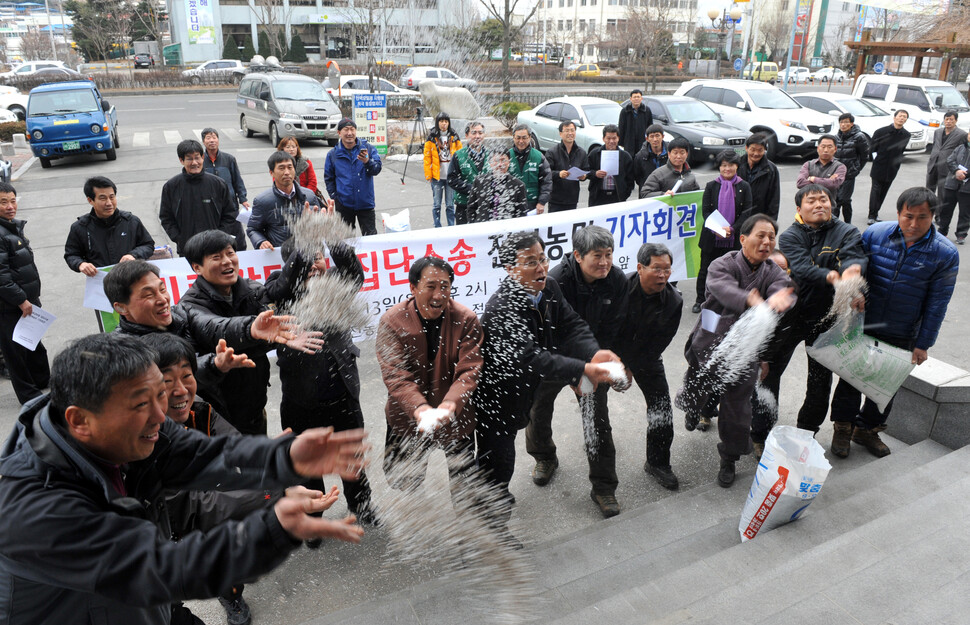 2012년 2월13일 전북 전주 농협 앞에서 열린 ‘비료 담합 소송 기자회견’에서 농민들이 담합에 항의하는 뜻으로 농협 현관에 비료를 뿌리고 있다. 연합뉴스