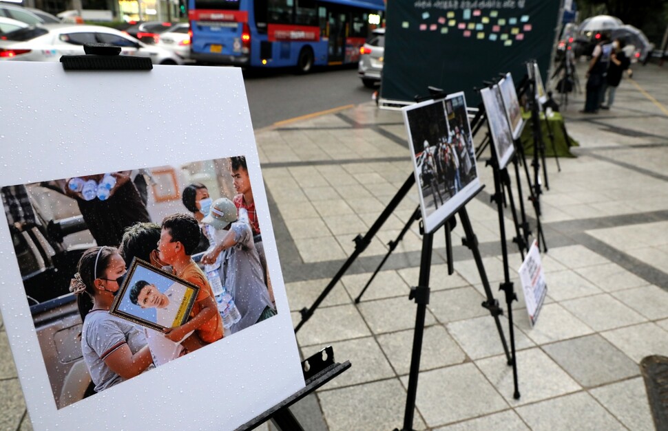 6월10일 미얀마 민주주의를 지지하는 한국시민사회단체모임이 서울 강남구 테헤란로 포스코센터 앞 거리에서 미얀마 투쟁을 기록한 사진을 전시했다. 우산 쓴 시민들이 이를 살펴보고, 뒤쪽 벽에는 시민들이 적은 연대 메시지가 붙어 있다. 류우종 기자