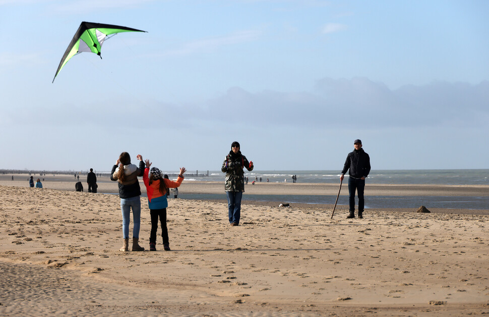 2024년 2월12일 네덜란드 제일란트주 오스트카펠러 해변에서 한 가족이 연날리기를 하고 있다. 그 뒤로 여유롭게 산책하는 관광객들이 보인다.