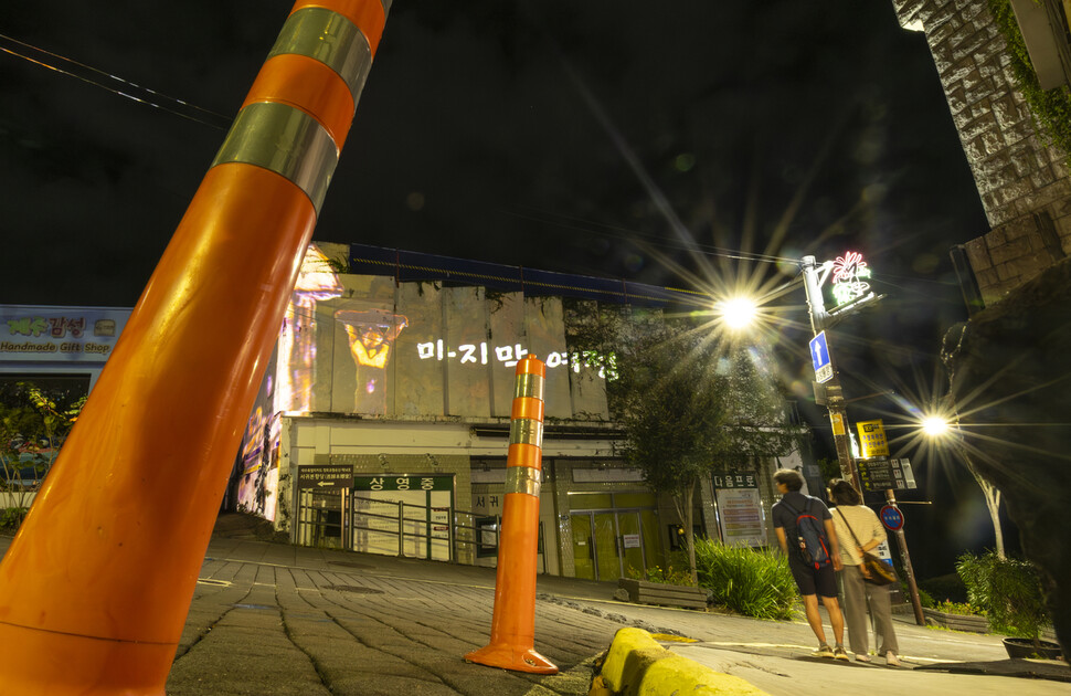 2025년 10월14일 저녁 제주 서귀포시 이중섭거리 중턱에 있는 서귀포관광극장의 낡은 외벽에 이중섭 작품으로 이루어진 미디어파사드 주제 ‘마지막 여정’이 투사되고 있다. 보존과 철거의 갈림길에 선 건물의 ‘마지막 상영회’처럼, 어두운 밤에 빛나는 강렬한 빛이 운명을 알 수 없는 극장의 존재감을 더욱 드러낸다.