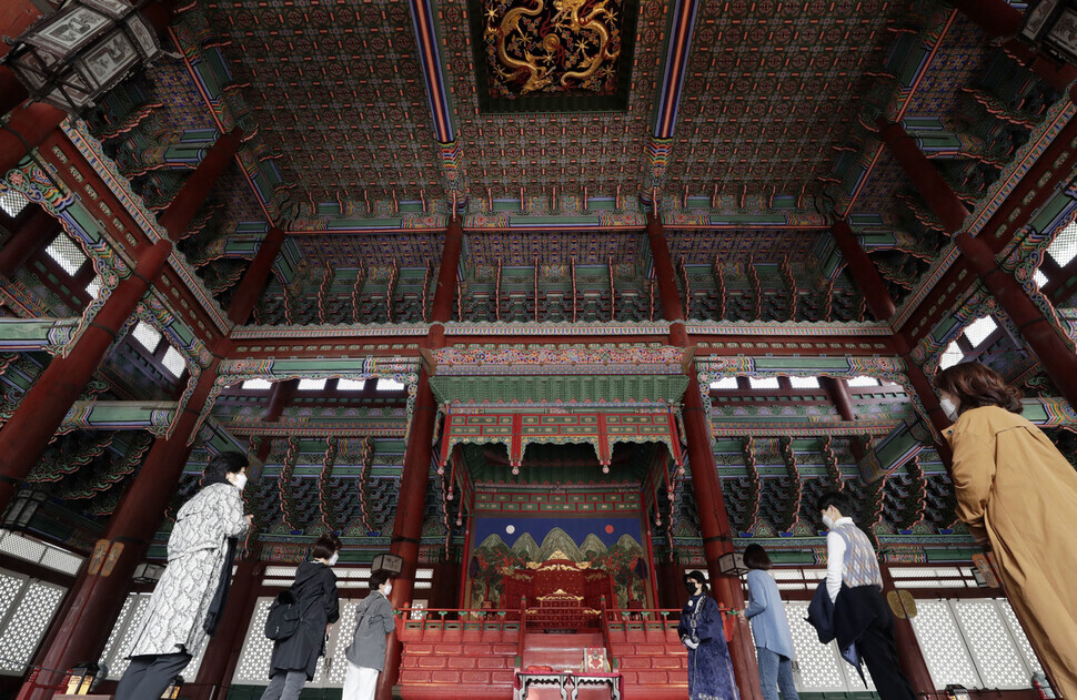 A professional guide educates visitors about Geunjeong Hall.