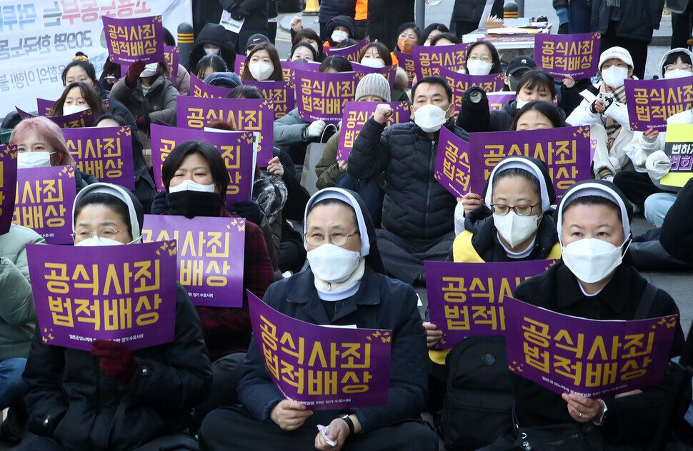 Participants in the 1,582nd Wednesday Demonstration on Feb. 8 hold up signs calling for a formal apology and legal compensation from Japan for victims of the “comfort women” system. (Kim Hye-yun/The Hankyoreh)
