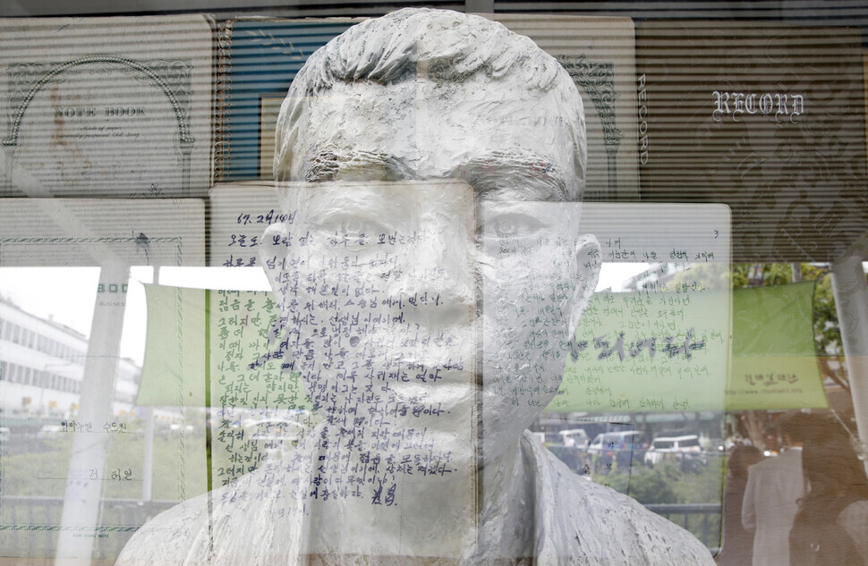 This double-exposure photo shows a statue of labor martyr Jeon Tae-il and his personal journal, displayed at Beodeul Bridge on Cheonggyecheon in Seoul. (pool photo)
