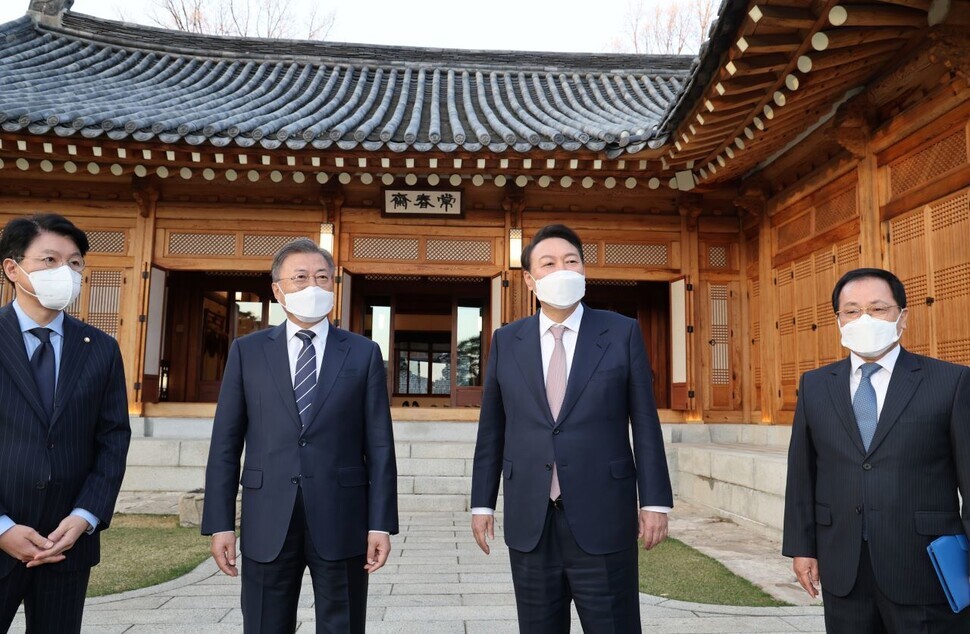 President Moon Jae-in and President-elect Yoon Suk-yeol speak while heading toward the Blue House’s Sangchunjae guest home for their meeting on March 28. On the far left is Chang Je-won, Yoon’s chief of staff, and on the far right is Yoo Young-min, Moon’s chief of staff. (Yonhap News)