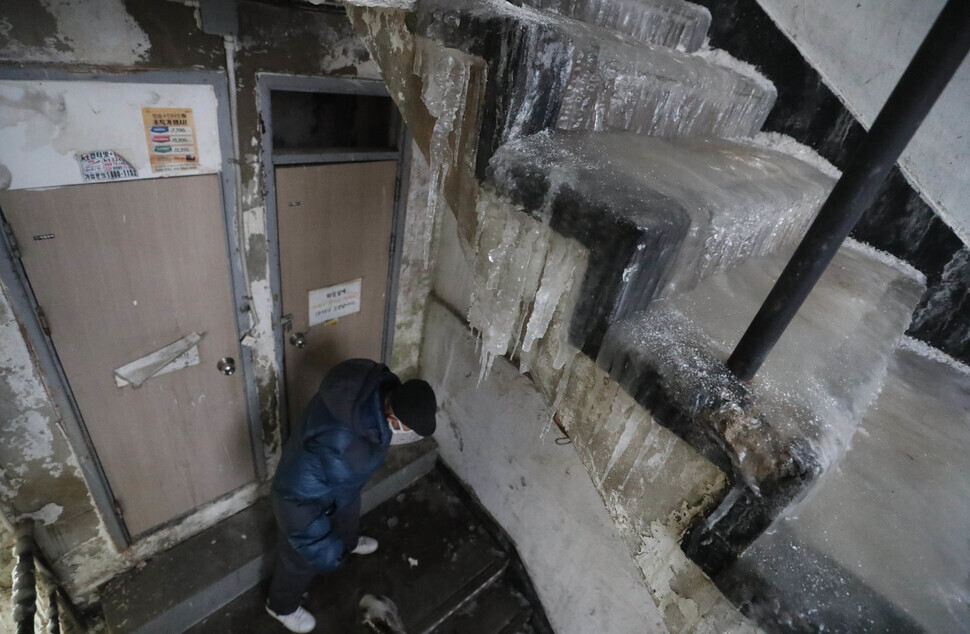 A resident of a flophouse in the Dongja neighborhood of Seoul’s Yongsan District carefully makes their way down the ice-covered stairway. (Kang Chang-kwang/The Hankyoreh)