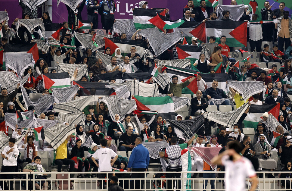 카타르 아시안컵에서 관중이 연대의 뜻을 담아 팔레스타인 국기와 전통 스카프(케피예)를 펼쳐 흔들고 있다.