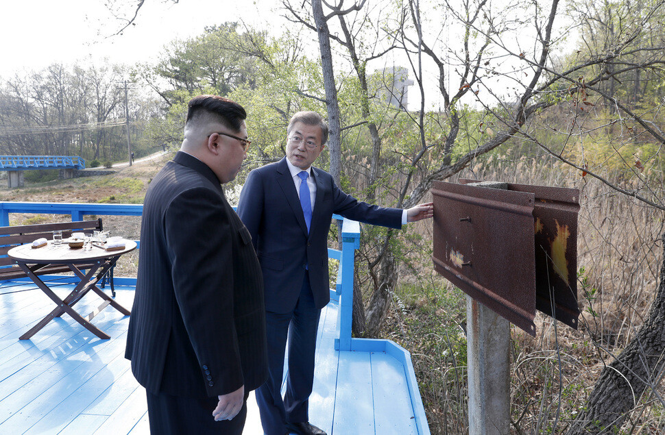 President Moon Jae-in speaks to North Korean leader Kim Jong-un about an old signpost at the far end of a pedestrian bridge in Panmunjeom during their summit on Apr. 27. (Photo Pool)